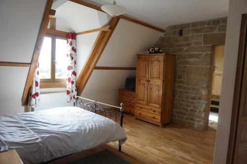a bedroom with a bed and a stone wall at Maison du Murphy in Sourdeval