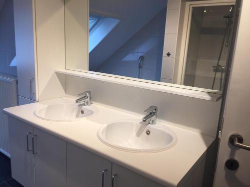 a bathroom with two sinks and a mirror at Maaszicht in Maasmechelen