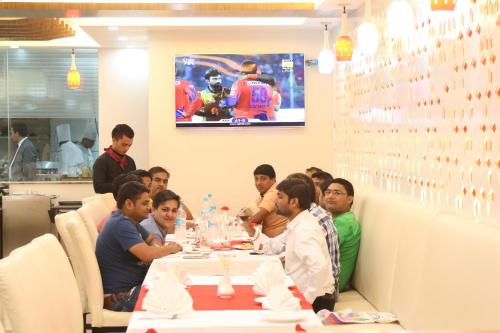 a group of people sitting around a table in a restaurant at Hotel Harrison Palace in Birātnagar