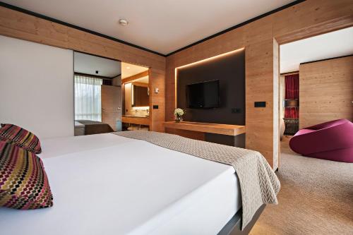 a bedroom with a white bed and a tv at Rikli Balance Hotel – Sava Hotels & Resorts in Bled