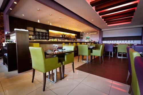 a dining room with green chairs and a bar at Mamba Point Hotel in Monrovia