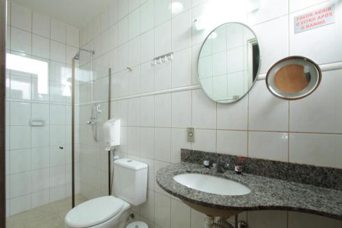 a bathroom with a toilet and a sink and a mirror at Hotel Malibu in São Carlos
