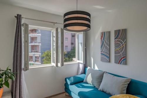 a living room with a blue couch and two windows at Chris's condo in Split