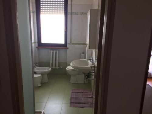 een badkamer met 2 toiletten, een wastafel en een raam bij Al Pontesel in Garda