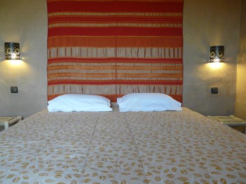 a bedroom with a large bed with two pillows at Tifina Caravanserail d'Arfoud in Erfoud