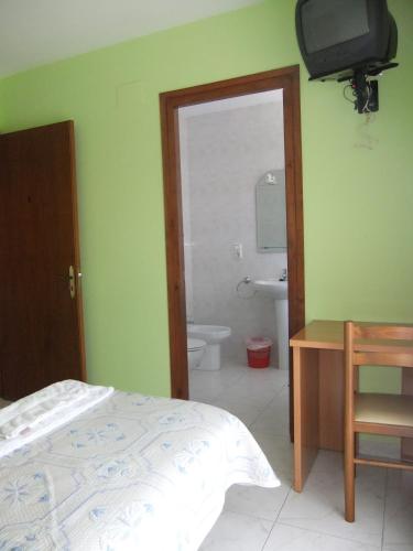 a bedroom with a bed and a bathroom with a television at Pensió L'Estada in Sant Joan les Fonts