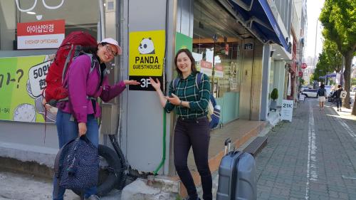 two women standing in front of a store holding a sign at Panda Guesthouse in Gwangju