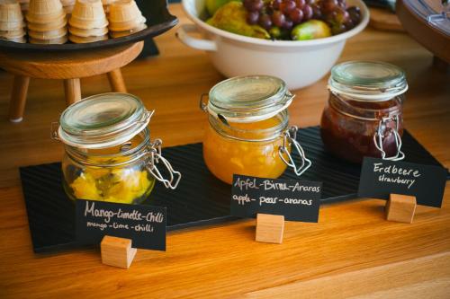 a table with three jars of honey and a bowl of fruit at Vienna House Easy by Wyndham Castrop-Rauxel in Castrop-Rauxel