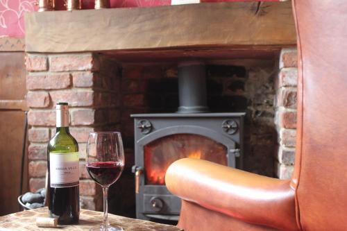 a glass of wine sitting on a table with a fireplace at Mallyan Spout Hotel in Goathland