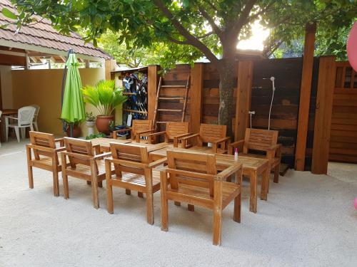 a group of wooden tables and chairs under a tree at Holiday Garden Rasdhoo in Rasdu