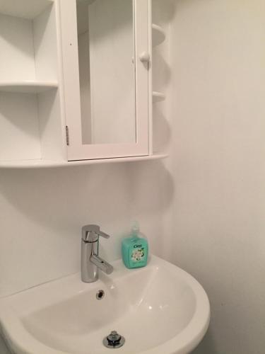 a bathroom sink with a white cabinet and a soap dispenser at Domsjö Apartment in Örnsköldsvik