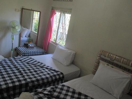 a room with two beds and two windows at ESA di Kubu Homestay in Singaraja