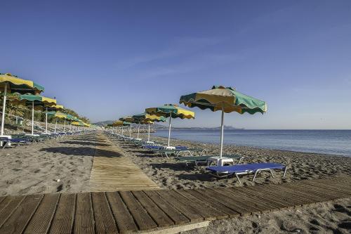 a row of umbrellas and chairs on a beach at Irene Palace Beach Resort in Kolymbia