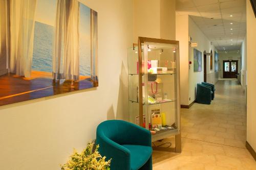 a hallway with a blue chair in a room at Fattoria La Principina Hotel & Congress in Principina Terra