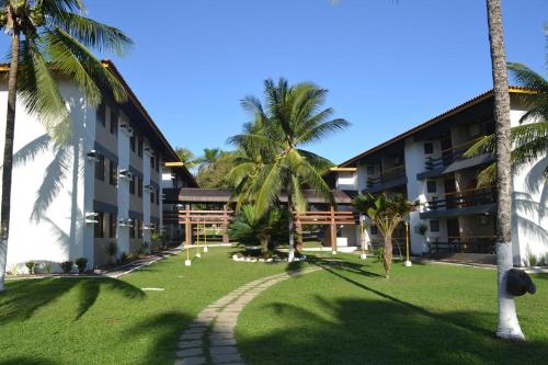 a resort with palm trees in front of a building at Casa Sol e Mar Beira-mar in Ilhéus
