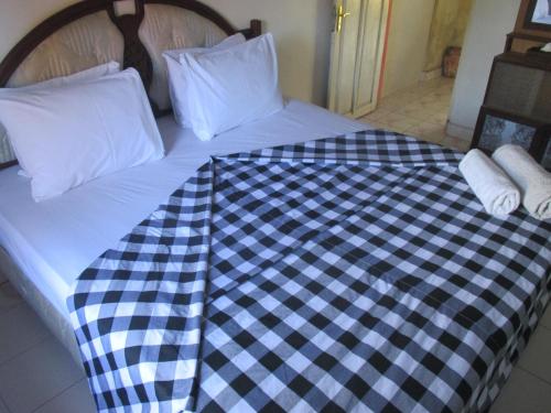 a bed with a black and white checkered blanket at ESA di Kubu Homestay in Singaraja