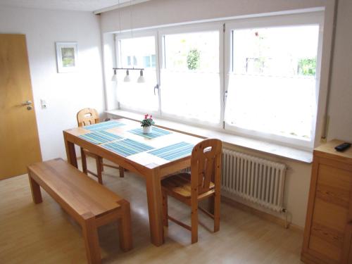 una sala da pranzo con tavolo e sedie e due finestre di Ferienwohnung Dettenhausen a Dettenhausen