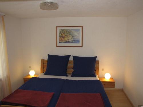 a bedroom with a bed with blue and red sheets and two lamps at Ferienwohnung Dettenhausen in Dettenhausen