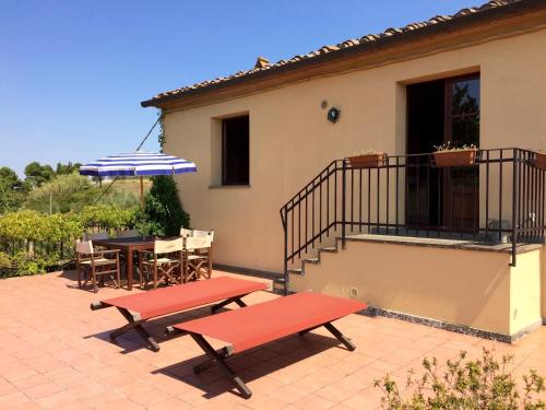 a patio with two benches and a table with an umbrella at Agriturismo La Palazzina in Palaia