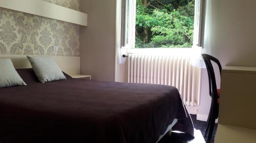 a bedroom with a bed in front of a window at Hôtel Saint Jean in Vals-les-Bains