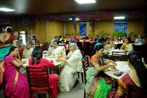 a group of people sitting at tables in a restaurant at Srivar Hotels in Guruvāyūr