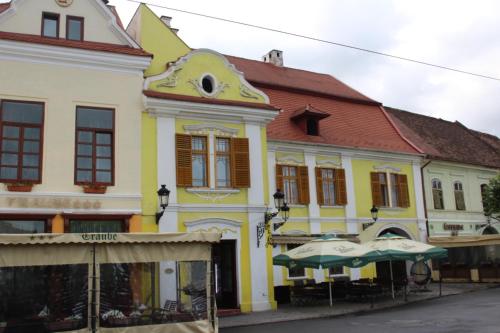 a yellow and white building with umbrellas in front of it at Ferdinand Apartments in Mediaş