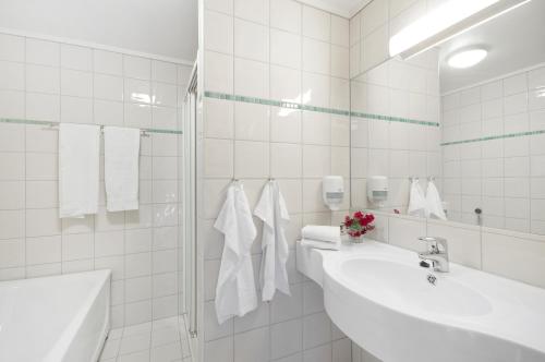 uma casa de banho em azulejos brancos com 2 lavatórios e um chuveiro em Farsund Fjordhotel em Farsund