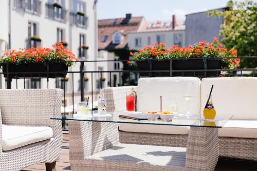 a glass table and chairs on a balcony with flowers at Hotel Brandenburger Tor Potsdam in Potsdam
