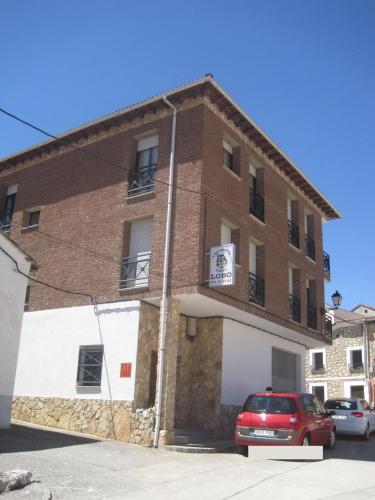 a red car parked in front of a brick building at Apartamento Rural Lobo in Ucero