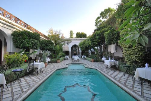 a swimming pool in a courtyard with tables and chairs at Palais Dar Donab in Marrakesh