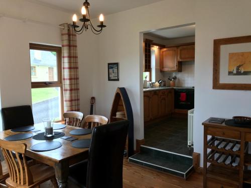 Kesh Lakeside Cottage في Kesh: غرفة طعام ومطبخ مع طاولة وكراسي