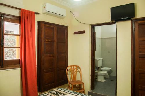 a room with a bathroom with a toilet and a television at Hostería La Pergola in Villa Serranita