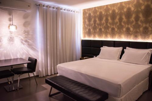 a bedroom with a large bed and a desk at Star Hotel in Itaperuna
