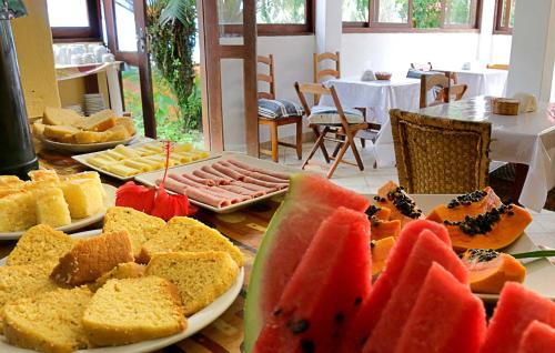 una mesa con platos de diferentes tipos de pan y fruta en Pousada Olhar da Sereia, en Arraial d'Ajuda