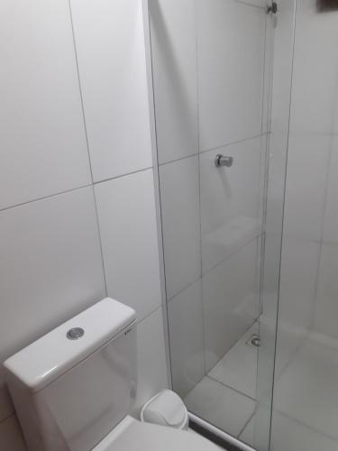 uma casa de banho branca com um chuveiro e um WC. em Pousada Eldorado em Lauro de Freitas