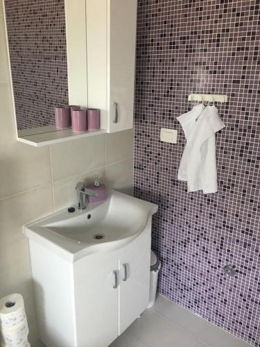 a bathroom with a sink and a tiled wall at Apartments 4you in Vir