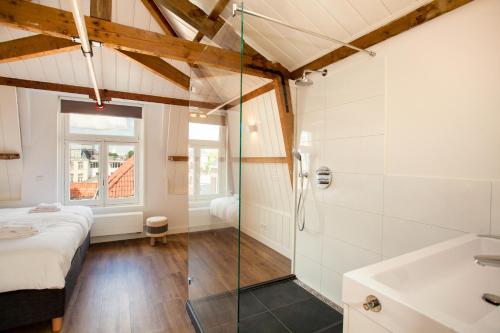 a bathroom with a shower and a bed and a sink at Stayci Serviced Apartments Royal Palace in The Hague