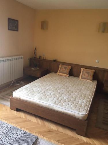 Cama grande en habitación con suelo de madera en Davidkov Holiday Home, en Shipka