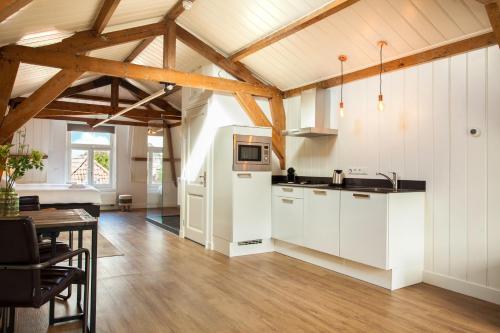a kitchen with white cabinets and a wooden ceiling at Stayci Serviced Apartments Royal Palace in The Hague