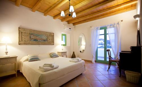 Un dormitorio con una gran cama blanca y una ventana. en Naoussa Bay Villas, en Naousa