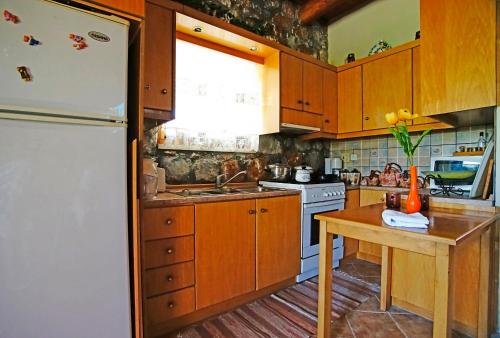 a kitchen with wooden cabinets and a white refrigerator at Mike Omalos Houses in Omalós