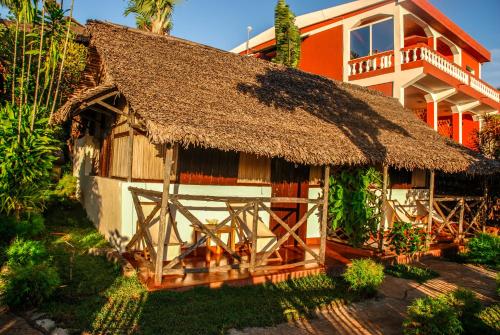 a house with a thatched roof and a building at Coucher de Soleil in Ambatoloaka
