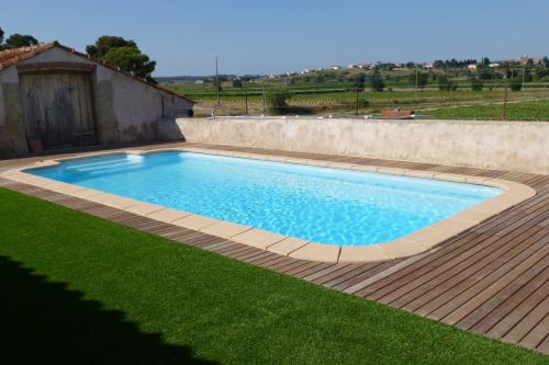 una piscina en un patio con césped verde en Le Domaine de Fraissinet, en Ouveillan