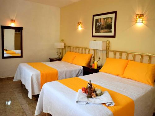 Habitación de hotel con 2 camas con sábanas de color naranja en Hotel San Antonio en Aguascalientes