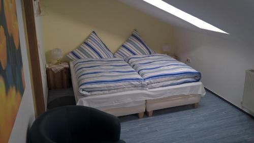 Bett mit blau und weiß gestreiften Kissen in einem Zimmer in der Unterkunft Pension-Roexe in Stendal