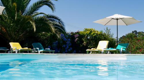a group of chairs and an umbrella next to a swimming pool at Quinta das Leiras - Rubiães in Paredes de Coura