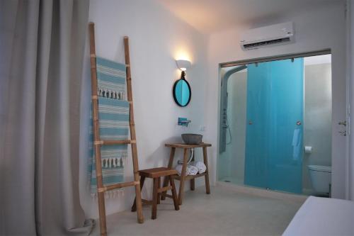 a bedroom with a ladder and a chair and a bathroom at Mykonos Moussa in Agios Ioannis Mykonos