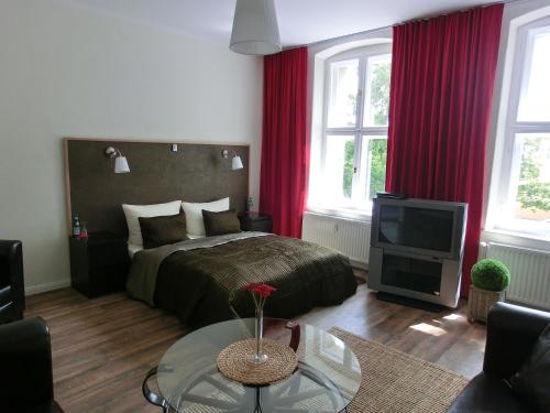 a bedroom with a bed with red curtains and a tv at Apartment KiezFlair in Potsdam