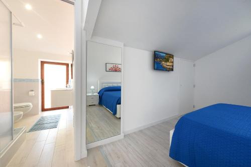 una camera bianca con letto blu e bagno di Marina Grande Inn a Sorrento