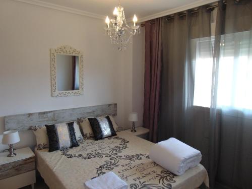a bedroom with a bed with a chandelier and a window at Apartamentos varios con 2 dorm en Marina Dor , la playa de Amplaries 47 , vista lateral al mar in Oropesa del Mar